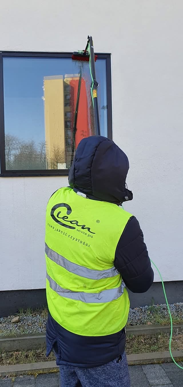 Pracownik Clean Service Pro myjący wysokie okno wodą demineralizowaną z poziomu terenu